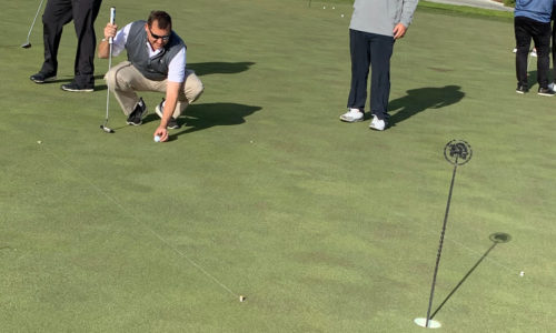 man placing golf ball on the golf green lining up a putt at the 2019 Reeves Complete Auto Center golf tournament